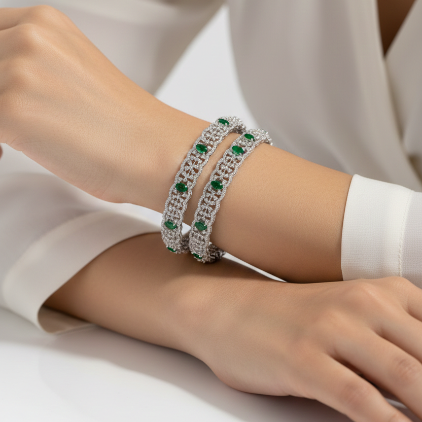 Close-up of a wrist wearing a silver bracelet with green gemstones on a white background