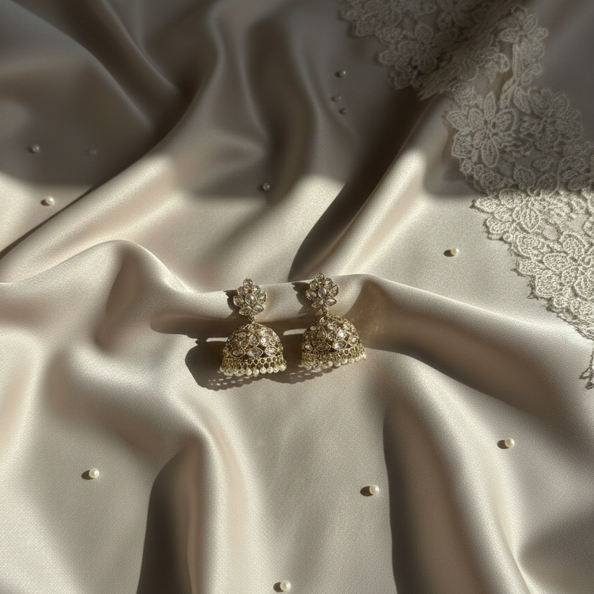 Gold earrings on a textured beige fabric surface