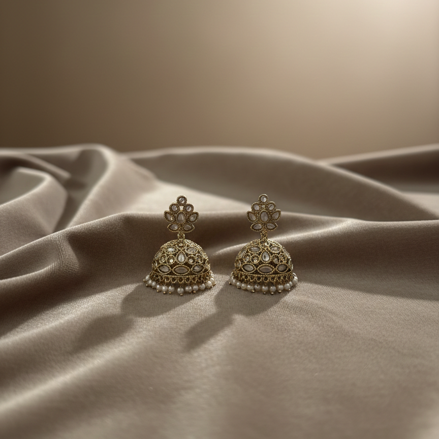 Pair of ornate earrings on a textured fabric surface