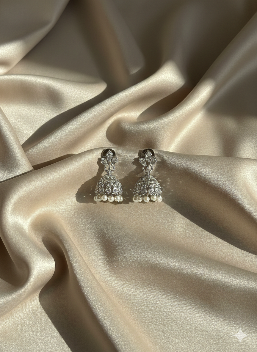 Silver earrings with pearls on a beige satin fabric
