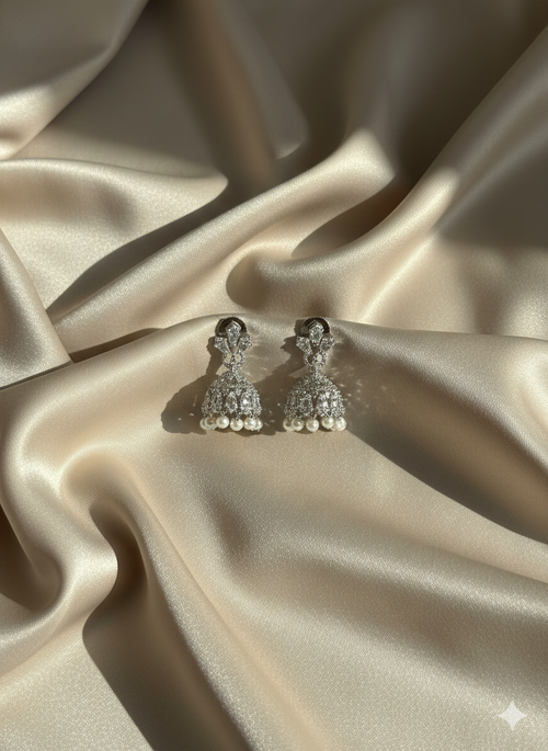 Silver earrings with pearls on a beige satin fabric