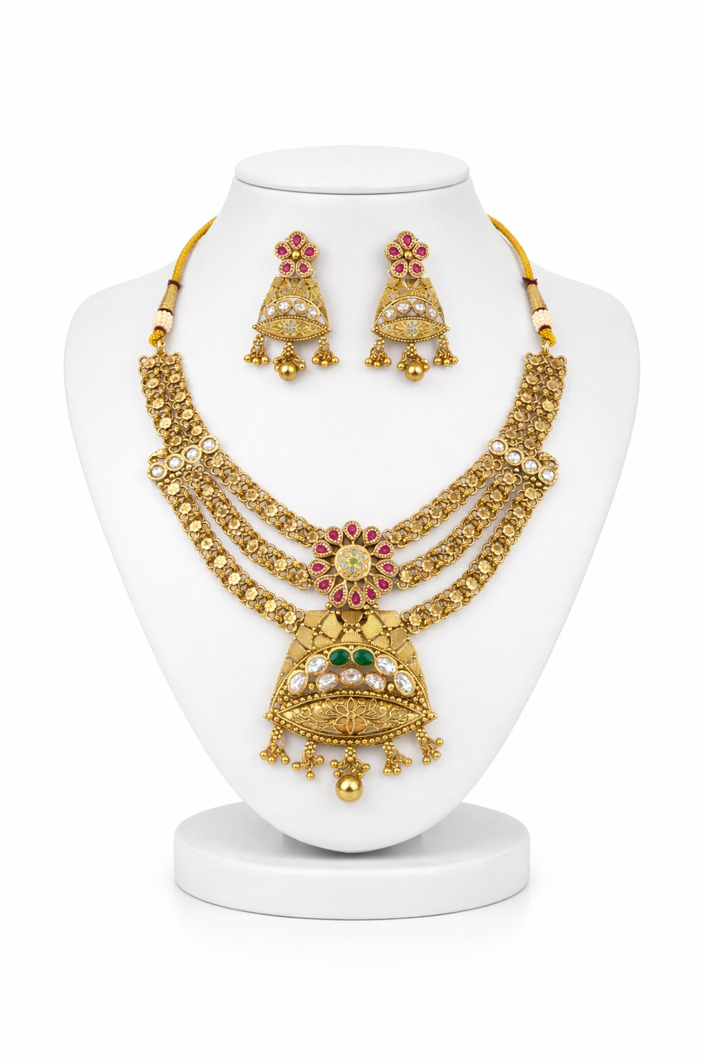 Gold jewelry set with necklace and earrings on a white stand