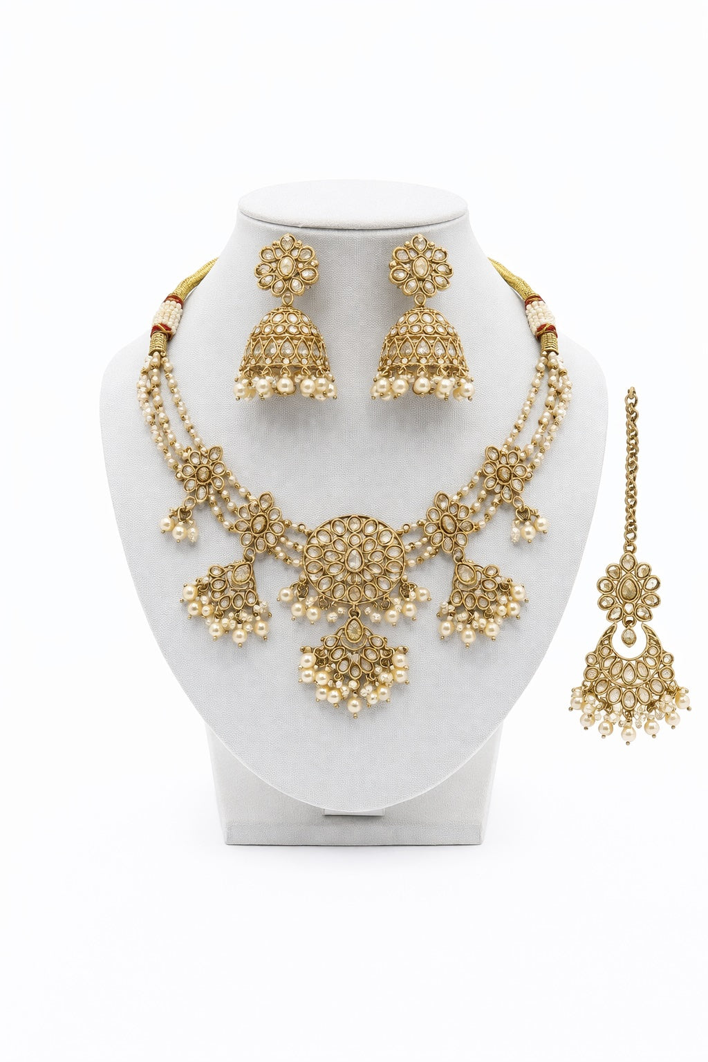 Gold necklace and earrings set on a white stand with a white background