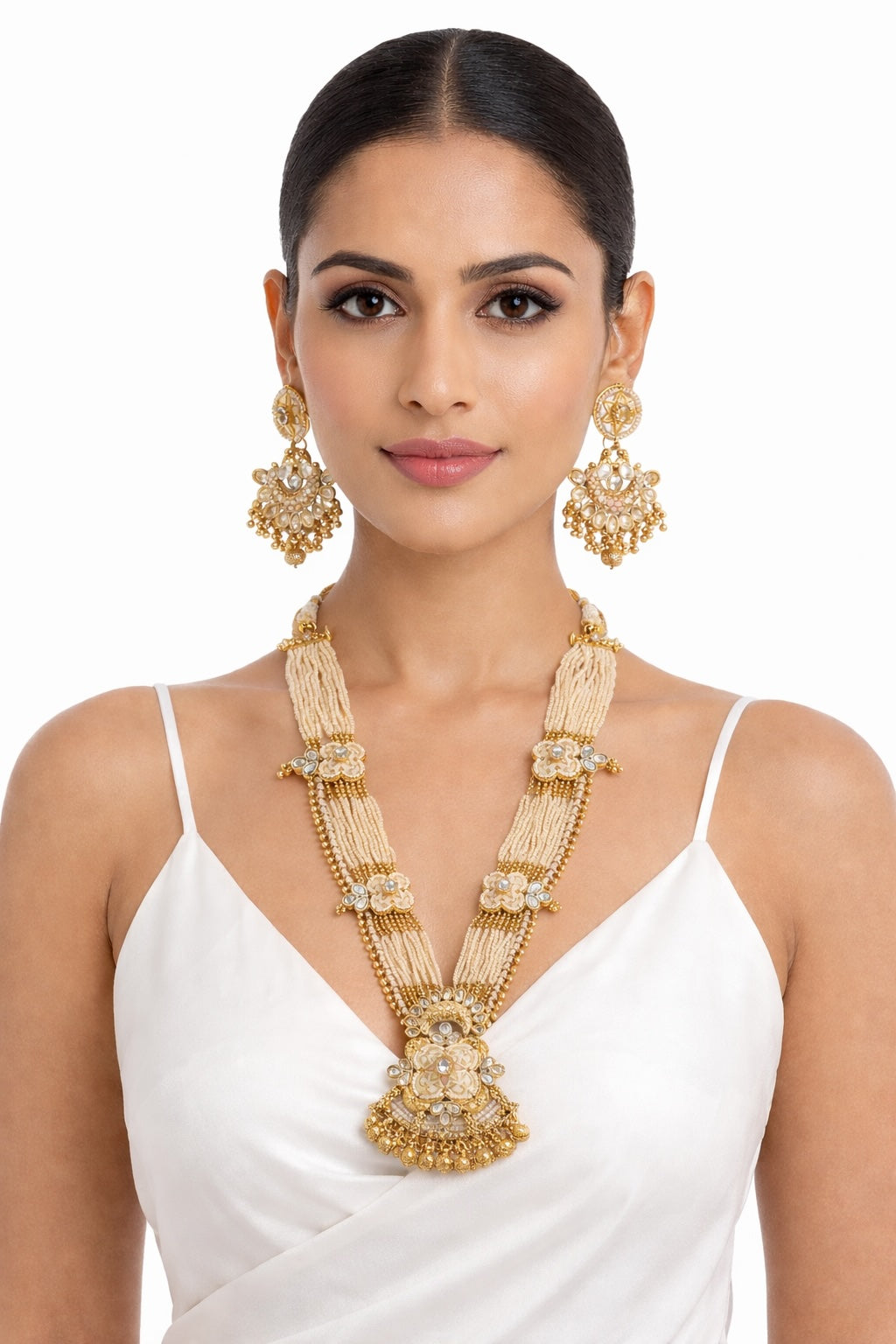 Woman wearing gold jewelry including a necklace, earrings, and a ring on a white background