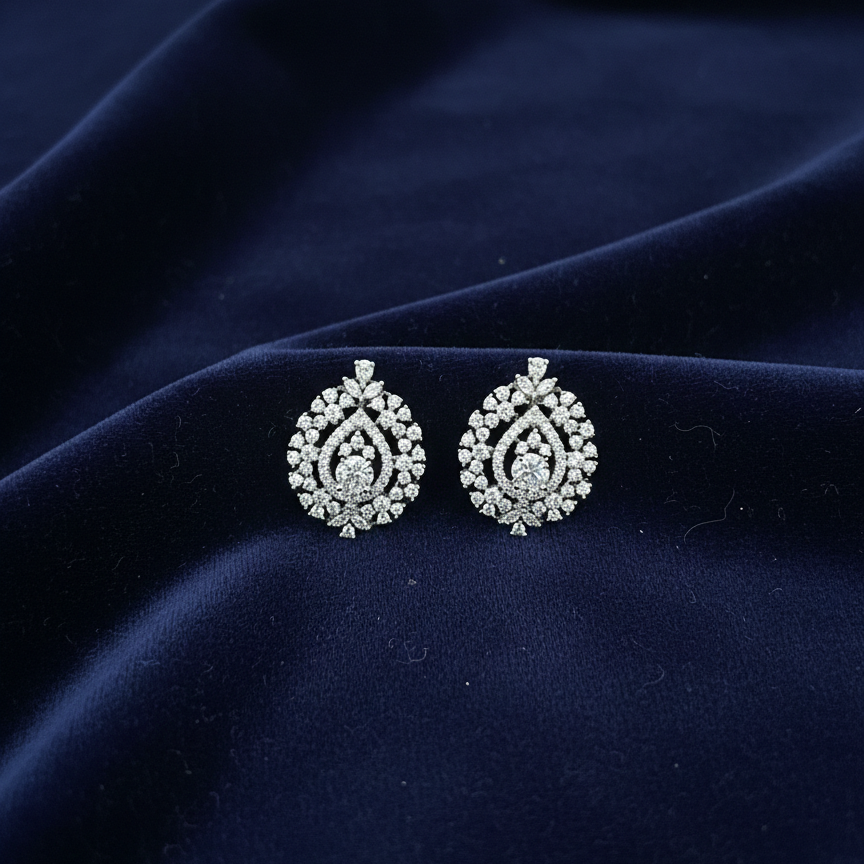 Pair of silver earrings on a dark blue fabric background