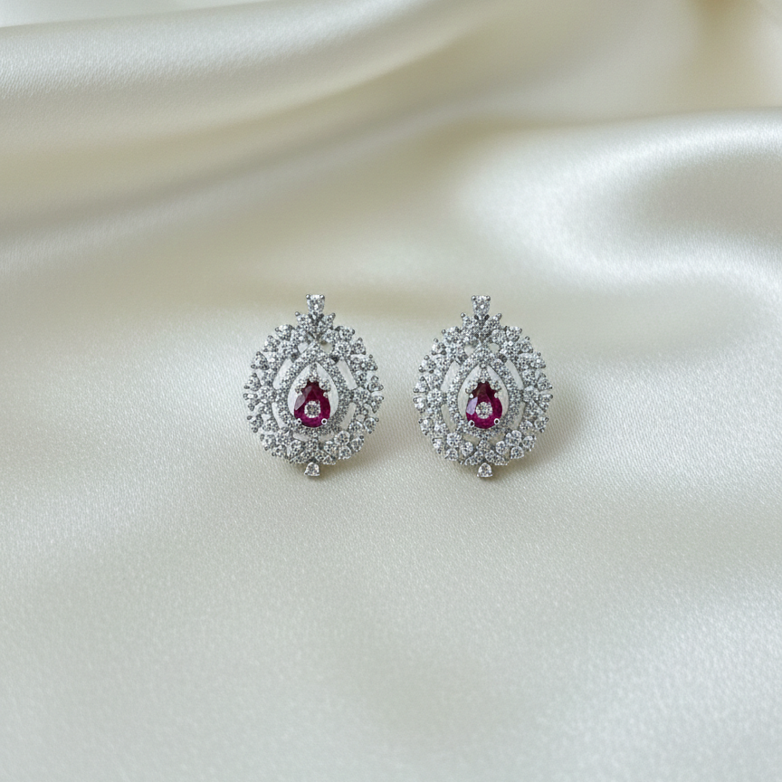 Pair of silver earrings with red gemstones on a white fabric background