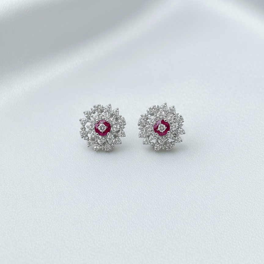 Pair of silver earrings with red gemstones on a white fabric background