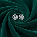 Pair of silver earrings on a dark green fabric background